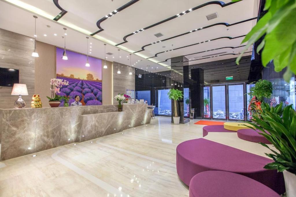 Lavande Hotel Wuhan Hanjiang Road Liuduqiao Metro Station في ووهان: ردهة بمقاعد أرجوانية في مبنى به نوافذ