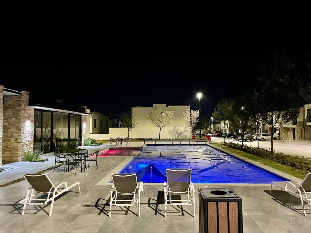eine Gruppe Stühle und ein Schwimmbad in der Nacht in der Unterkunft Habitación privada en zona residencial, El Marques in Miranda