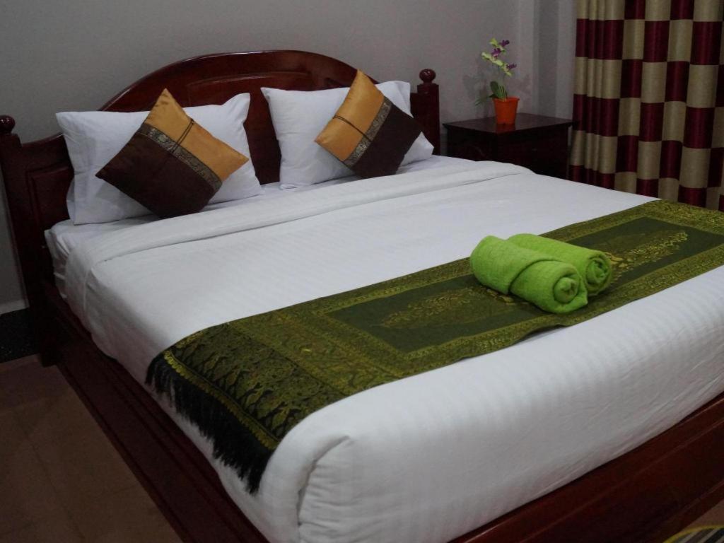 a bed with a green towel on top of it at Phetphaylin Hotel in Pakse