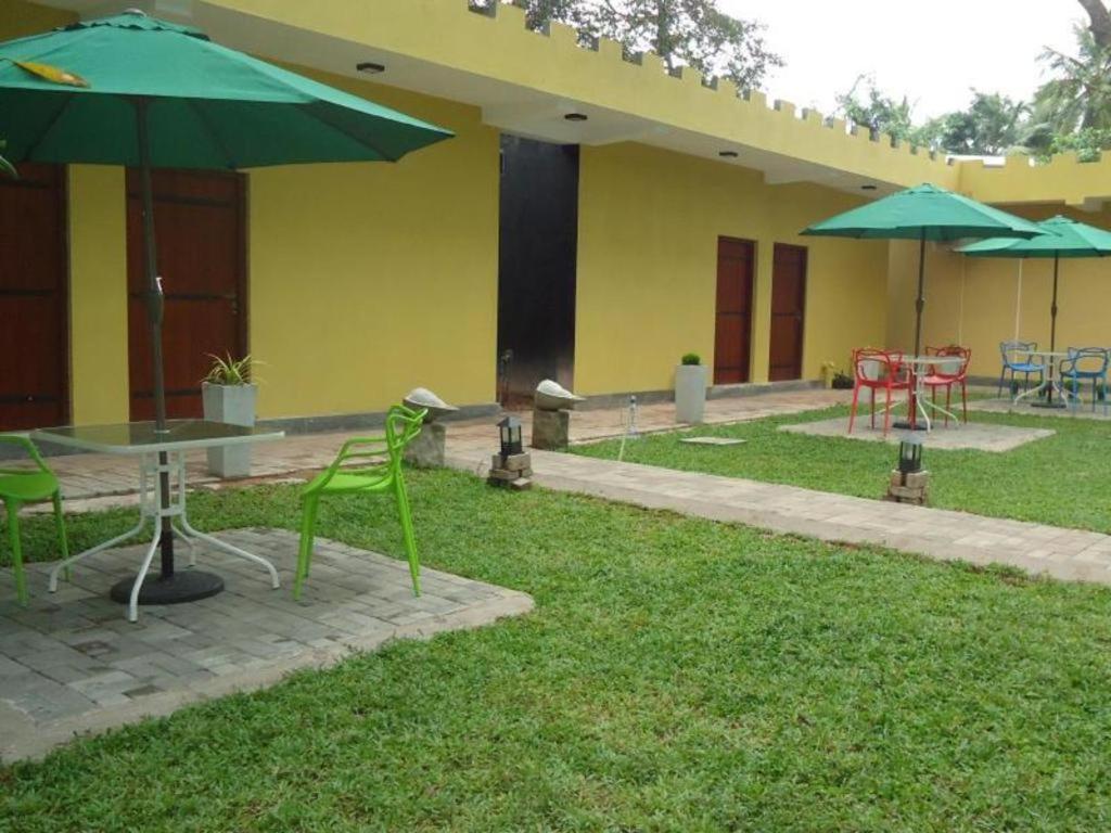 a patio with a table and chairs and umbrellas at Bridge Hotel Negombo in Dagonna