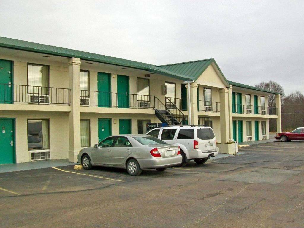 two cars parked in a parking lot in front of a building at America's Best Inn - Brinkley in Brinkley
