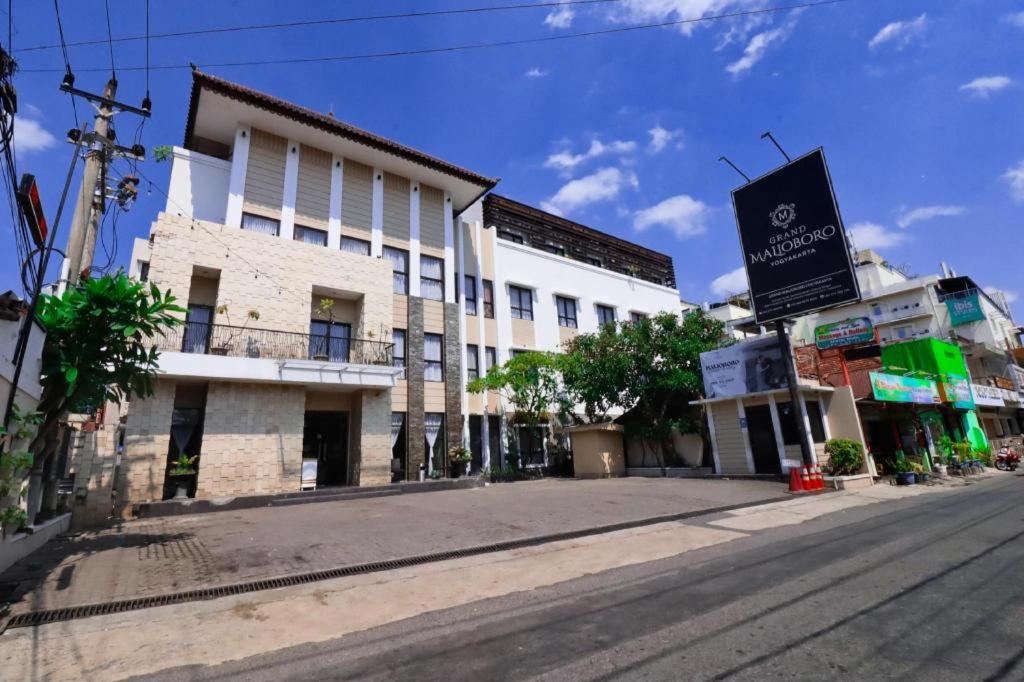 an empty street next to a white building at Grand Malioboro Yogyakarta in Yogyakarta