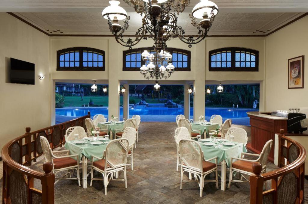a dining room with tables and chairs and a chandelier at eL Hotel Kartika Wijaya Batu in Songgoriti