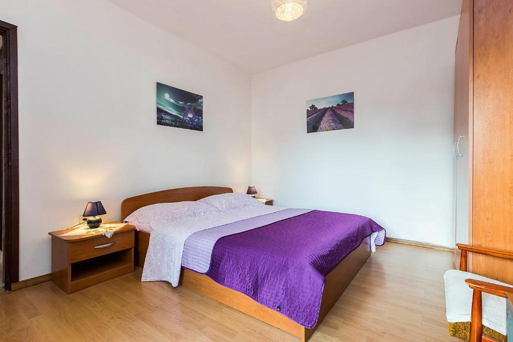 a bedroom with a bed with a purple blanket at Apartments Draga in Sukošan