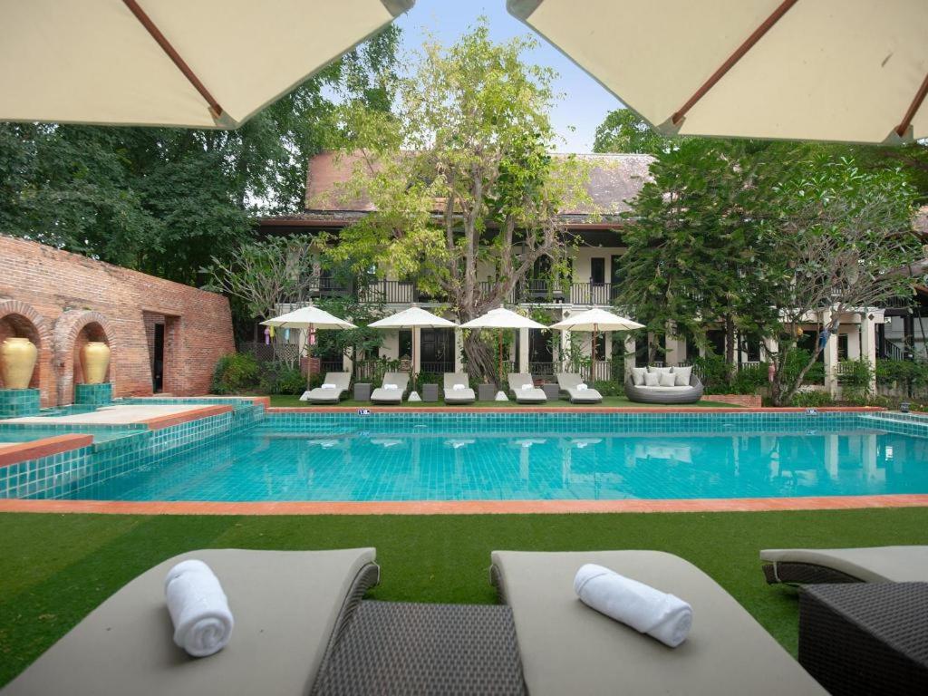 ein großer Swimmingpool mit Liegen und Sonnenschirmen in der Unterkunft B2 Suthep Night Market Premier Resort in Chiang Mai