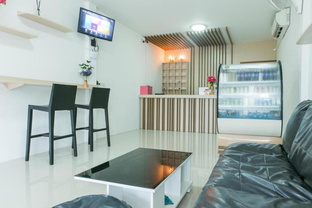 una sala de estar con un sofá y una mesa en Cheaper Room, en Surat Thani