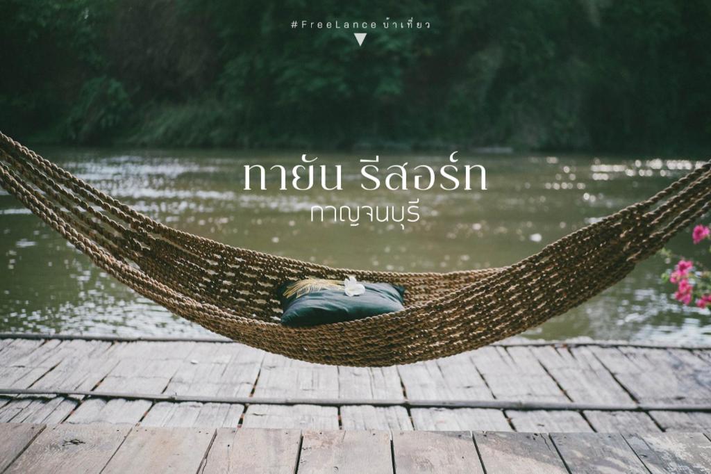 une personne dormant dans un hamac près d'un plan d'eau dans l'établissement Tayan Resort Kanchanaburi, à Ban Kao