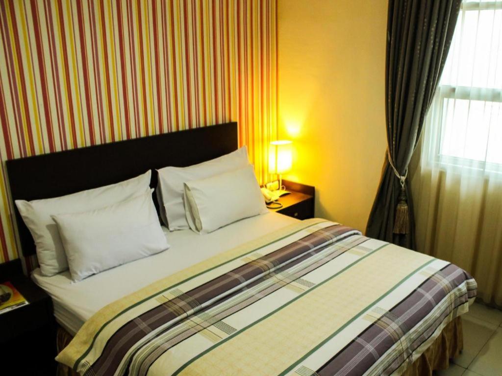 a bedroom with a large bed with white pillows at Vindhika Hotel in Makassar