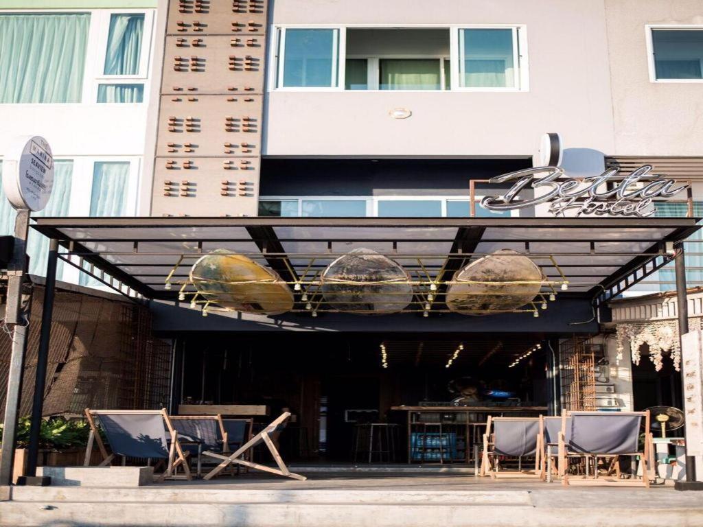 awning with chairs and a table in front of a building at Betta Hostel in Ban Thai Don (1)