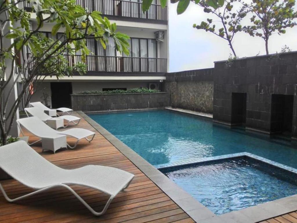 a swimming pool with white chairs on a wooden deck at D'Anaya Hotel Bogor in Bogor