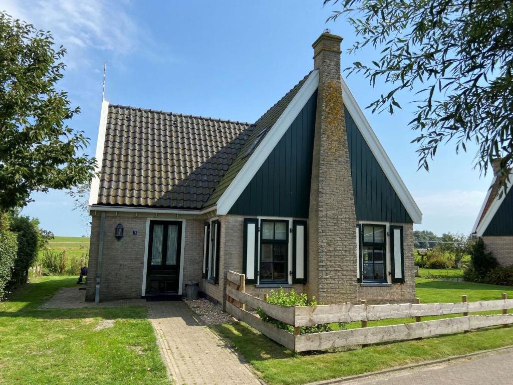 a small brick house with a gambrel roof at Holiday Home Wiringherlant-2 by Interhome in Noordstroe