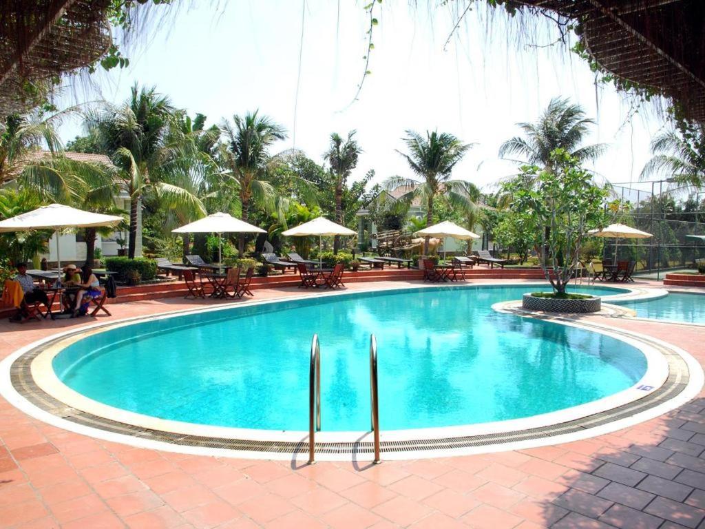 ein großer Pool mit Tischen und Sonnenschirmen in der Unterkunft Sao Mai Phu My Resort in Phú Mỹ