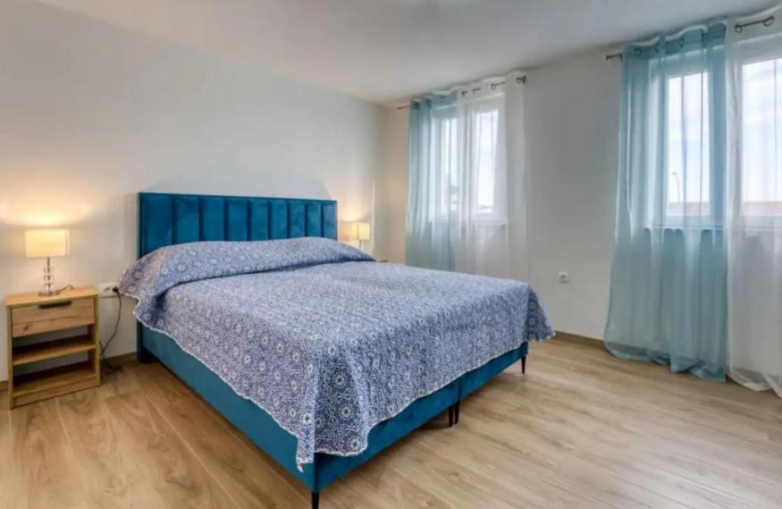 Apartment with sea view في أوباتيا: غرفة نوم بسرير ازرق ونوافذ