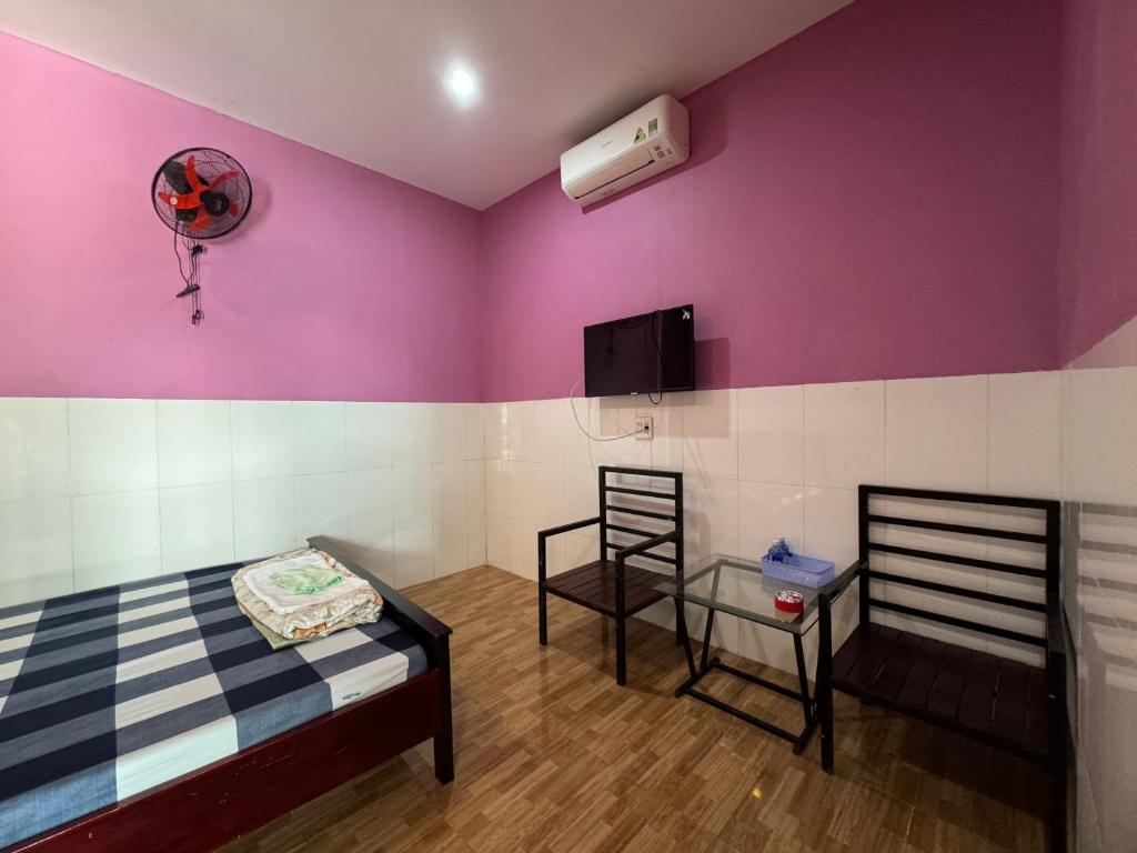 a room with a bed and a wall with a fan at Nhà Nghĩ Huỳnh Yên in Trà Vinh