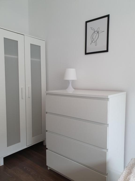 eine weiße Kommode mit einer Lampe darüber in der Unterkunft Apartament Nowy Port 7 in Gdańsk Letnica