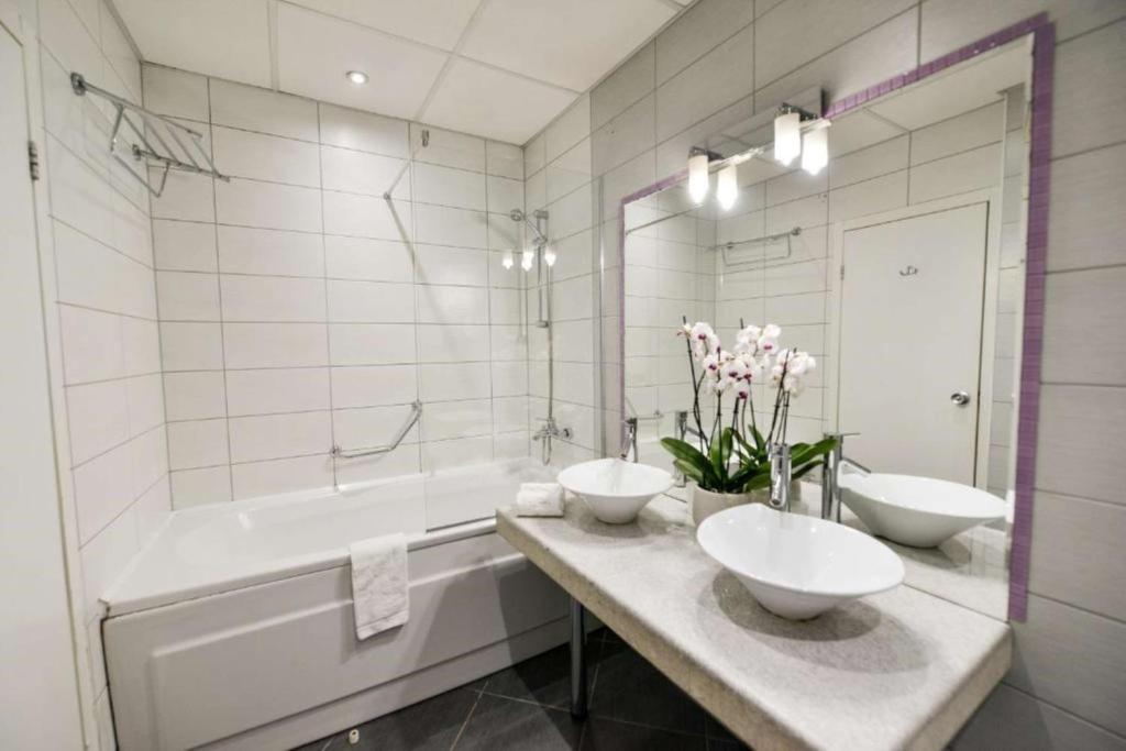 a white bathroom with two sinks and a tub and a tubermott at Art Plaza Hotel in Sofia