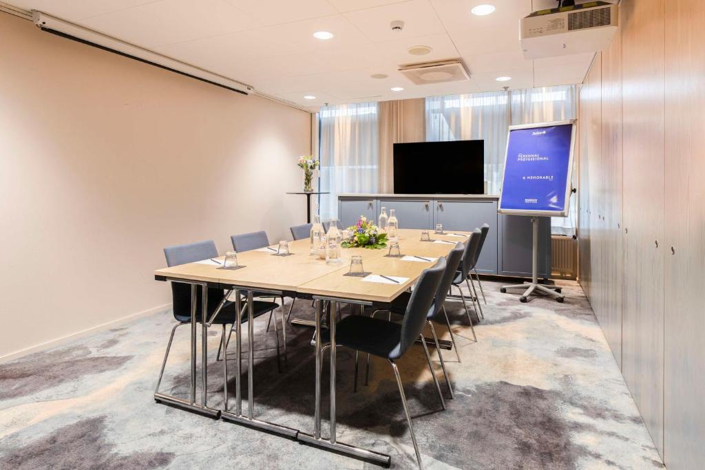 a conference room with a table and chairs and a screen at Radisson Blu Seaside Hotel, Helsinki in Helsinki