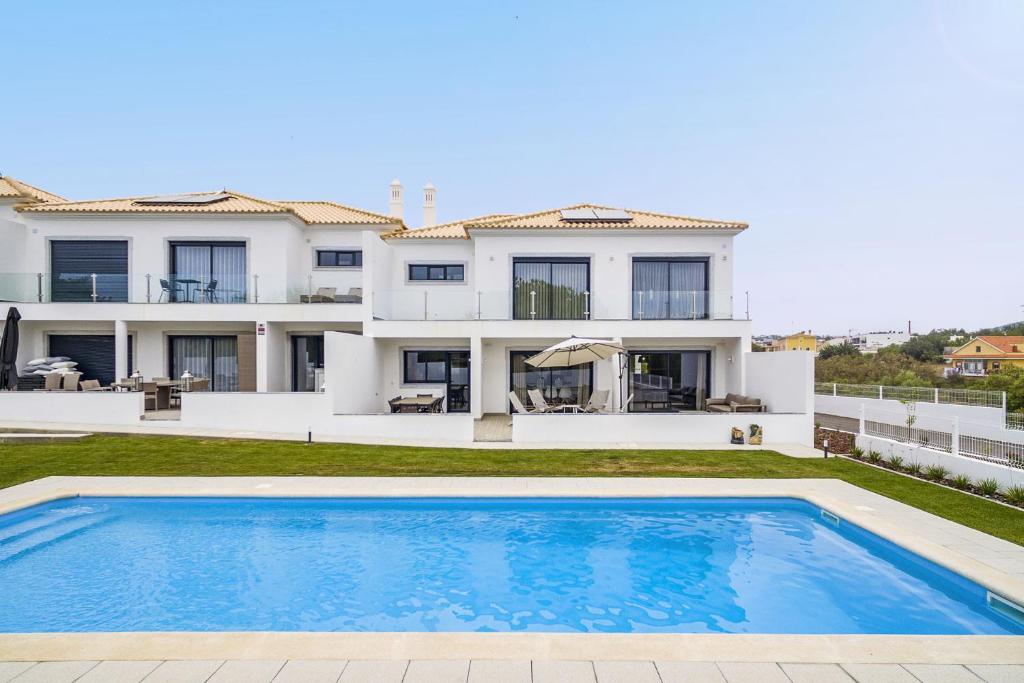 a villa with a swimming pool in front of a house at Almancil Elegant Villa With Pool by Homing in Almancil