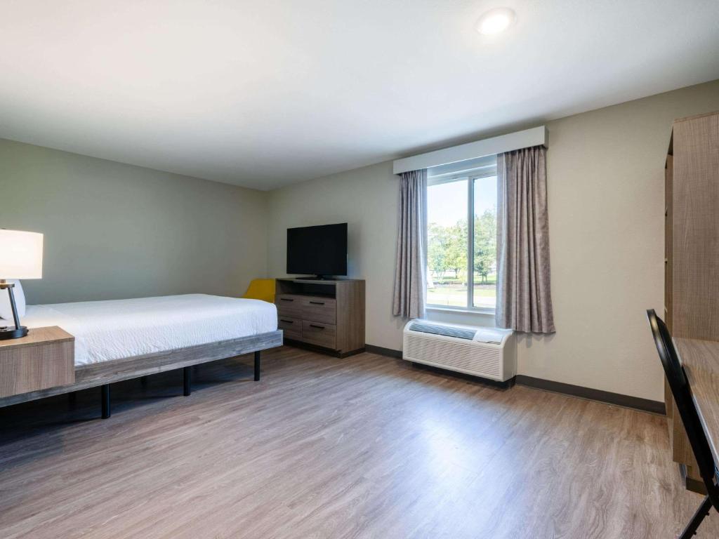 a bedroom with a bed and a tv and a window at ECHO Suites Extended Stay by Wyndham Spartanburg in Spartanburg