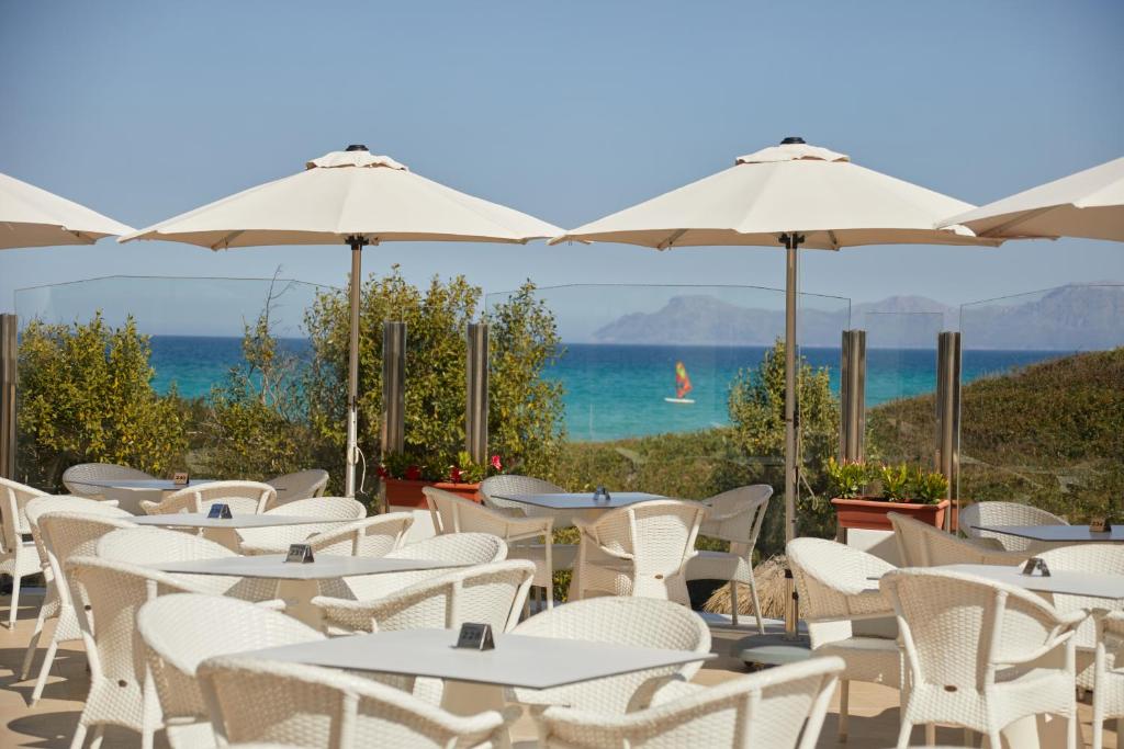 a row of tables and chairs with umbrellas and the ocean at Playa Esperanza Resort Affiliated by Meliá in Playa de Muro