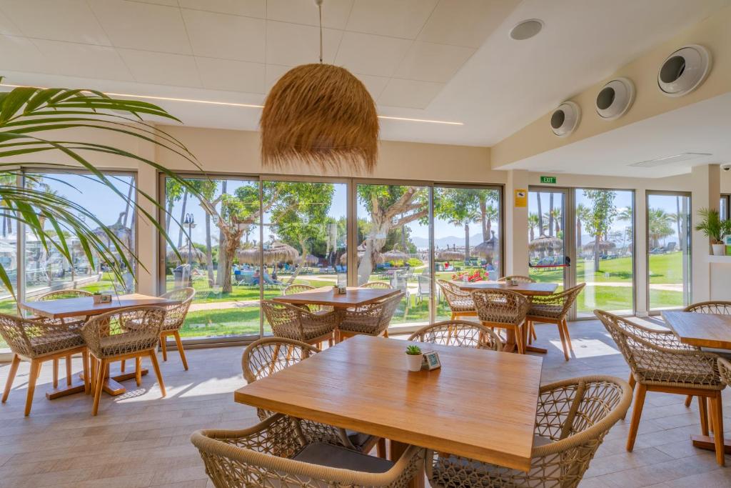 a restaurant with tables and chairs and a large window at Playa Esperanza Resort Affiliated by Meliá in Playa de Muro