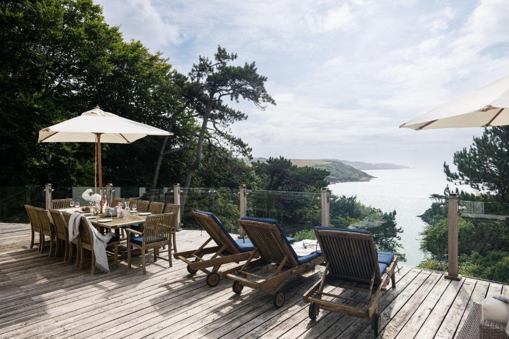 a wooden deck with a table and chairs and an umbrella at The Wood in Salcombe