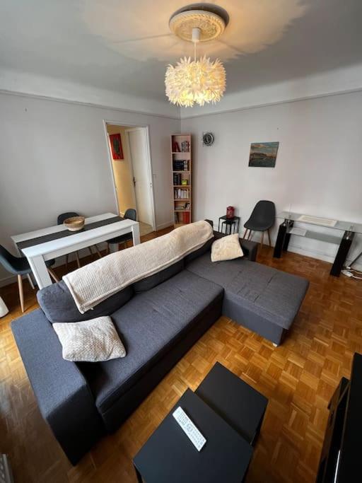 a living room with a blue couch and a chandelier at le nid berruyer en centre-ville in Bourges