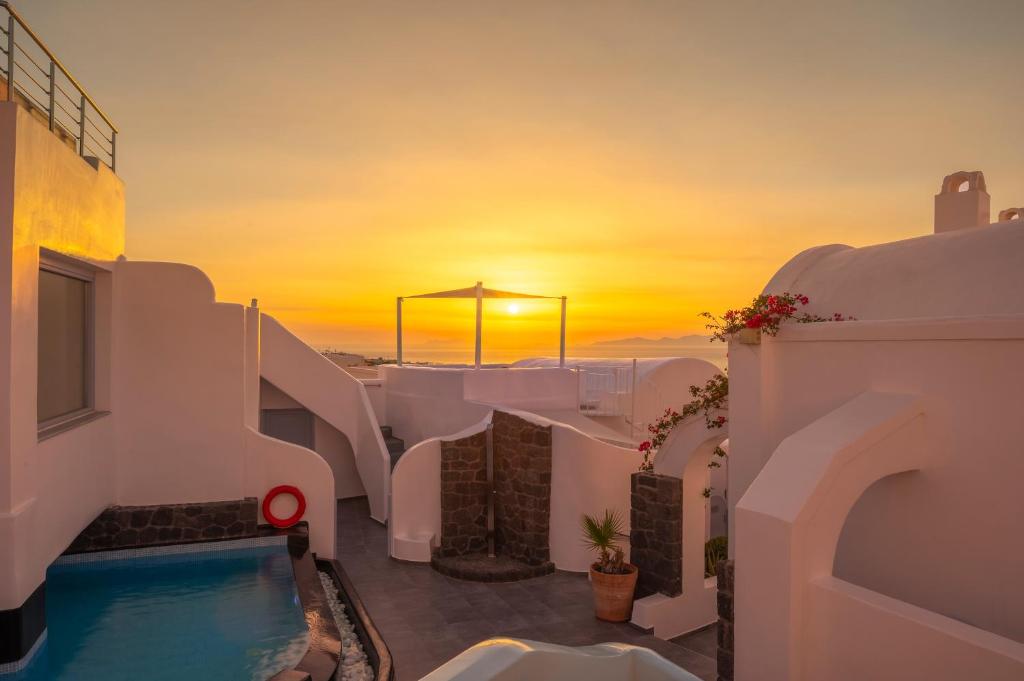 puesta de sol sobre el océano desde una casa con piscina en Sole d&#39;oro Luxury Suites, en Oia