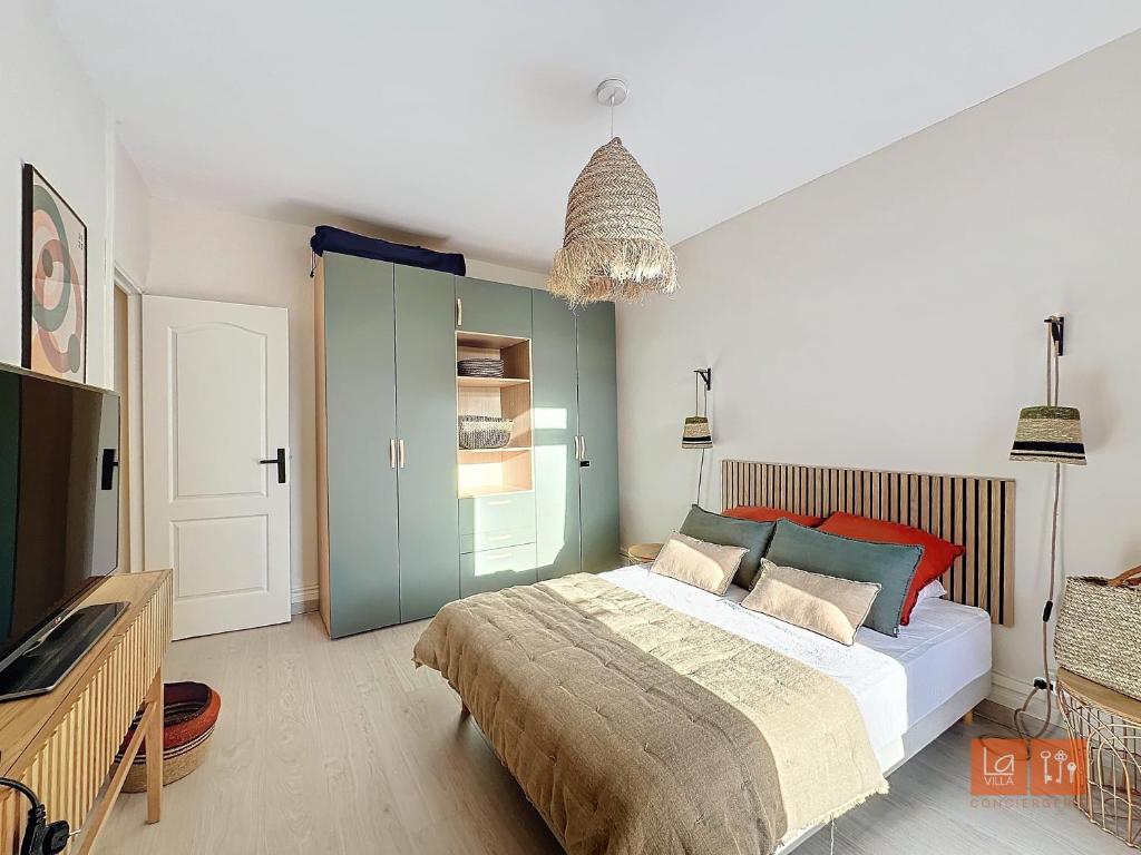 een slaapkamer met een groot bed en een televisie bij Le Mourillon - Centre Ville in Wimereux