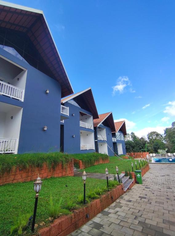 a row of blue buildings with a green lawn at The Caligo resort coorg in Madikeri