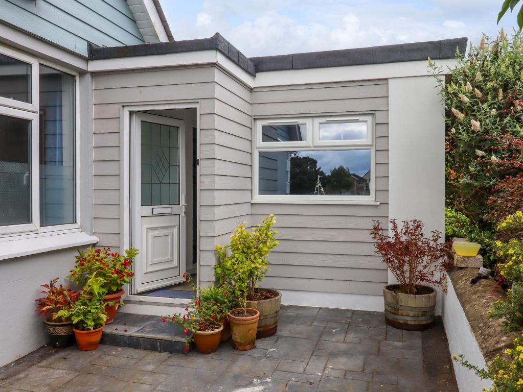 a white house with potted plants on a patio at Brixham Breeze Cabin in Brixham