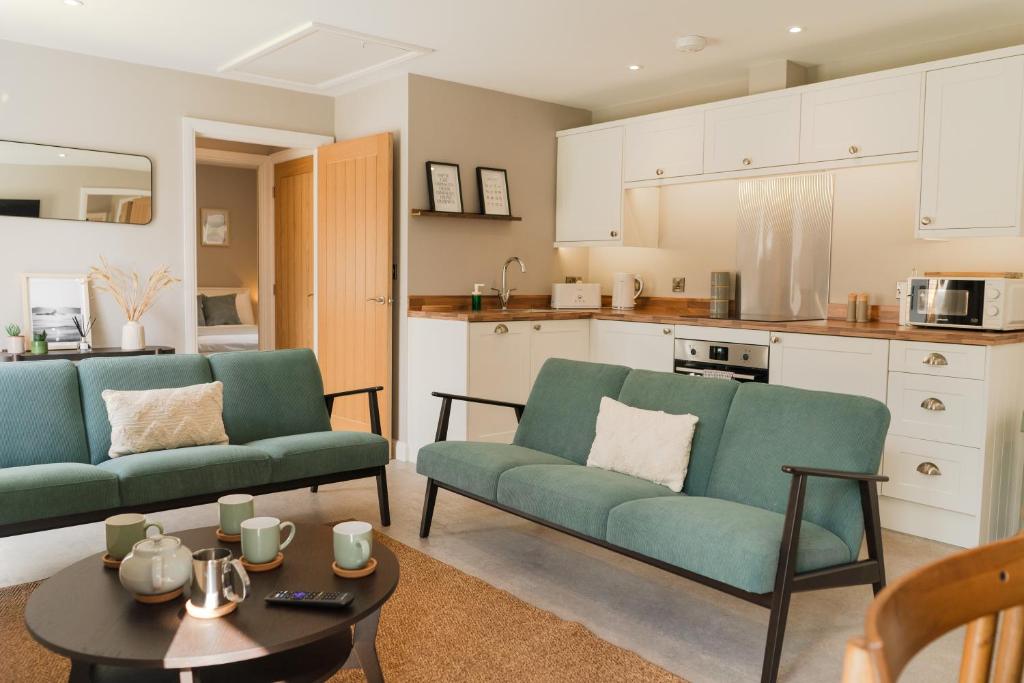 a living room with two green couches and a table at Fieldside Cottage in Scarborough