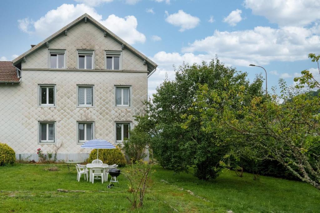 une maison avec une table et un parasol dans la cour dans l'établissement Les Proyes - Appt pour 6 avec jardin, à La Bresse
