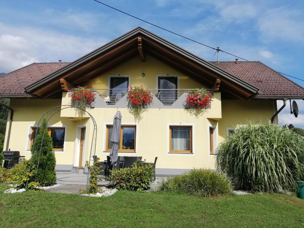 a yellow house with two windows with flower boxes at Terezia-Appartements Nassfeld in Hermagor