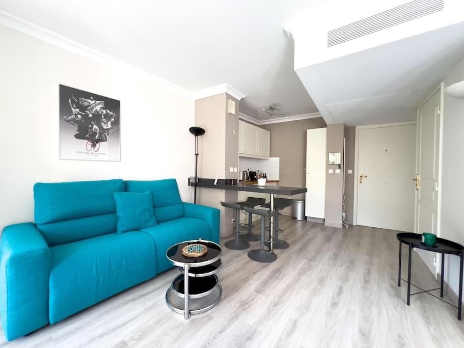 un salon avec un canapé bleu et une table dans l'établissement Charmant Studio avec terrasse et vue arborée, à Cannes