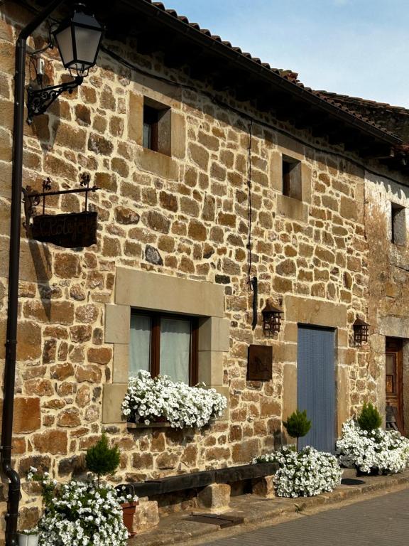 a stone building with two windows with white flowers at Casa Rural El Rotejar in El Royo