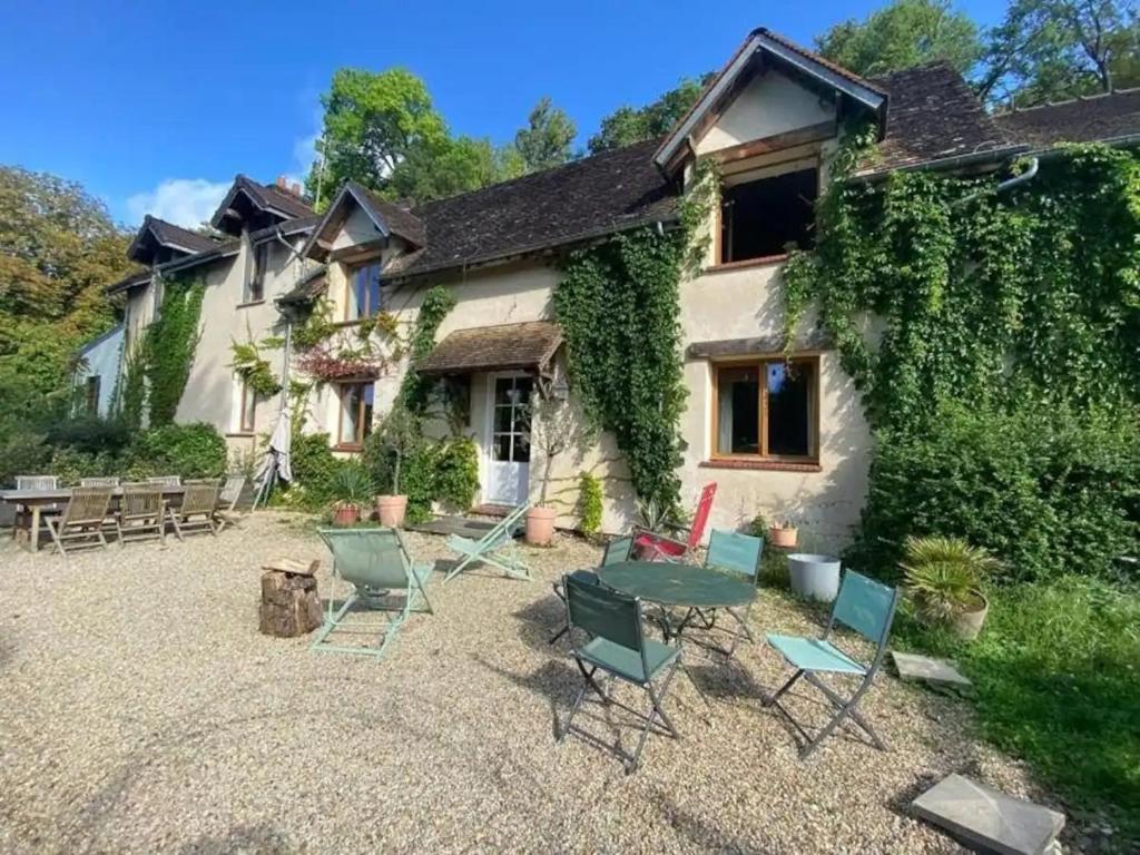 une maison avec des chaises et une table devant elle dans l'établissement La Grange - Hameau de Montmelian, à Vulaines-sur-Seine