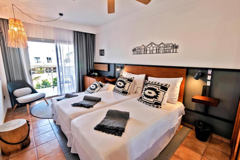 a hotel room with two beds and a chair at Coral Cotillo Beach in El Cotillo