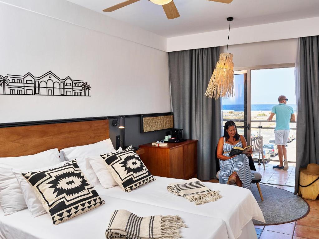 a woman sitting in a hotel room with a bed at Coral Cotillo Beach in El Cotillo