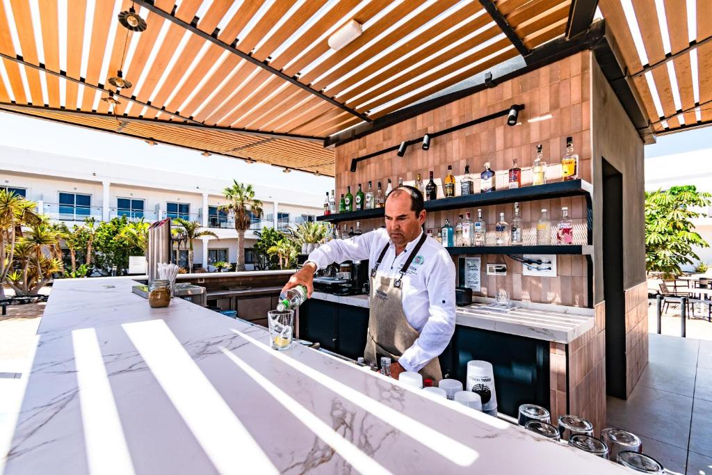 a bartender making a drink at a bar at Coral Cotillo Beach in El Cotillo
