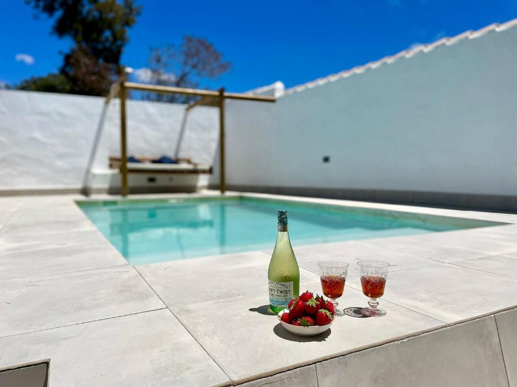 a bottle of wine and two glasses on a table next to a pool at Minichalet El Molino 5 in Chiclana de la Frontera