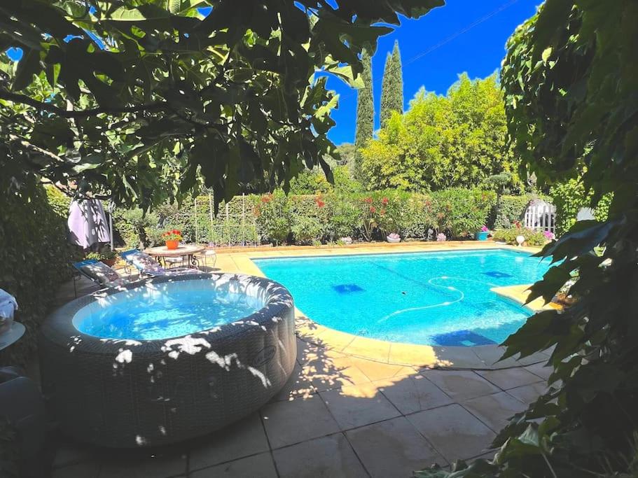 a swimming pool in a yard with a large tree at le jardin de mae in Bouc-Bel-Air