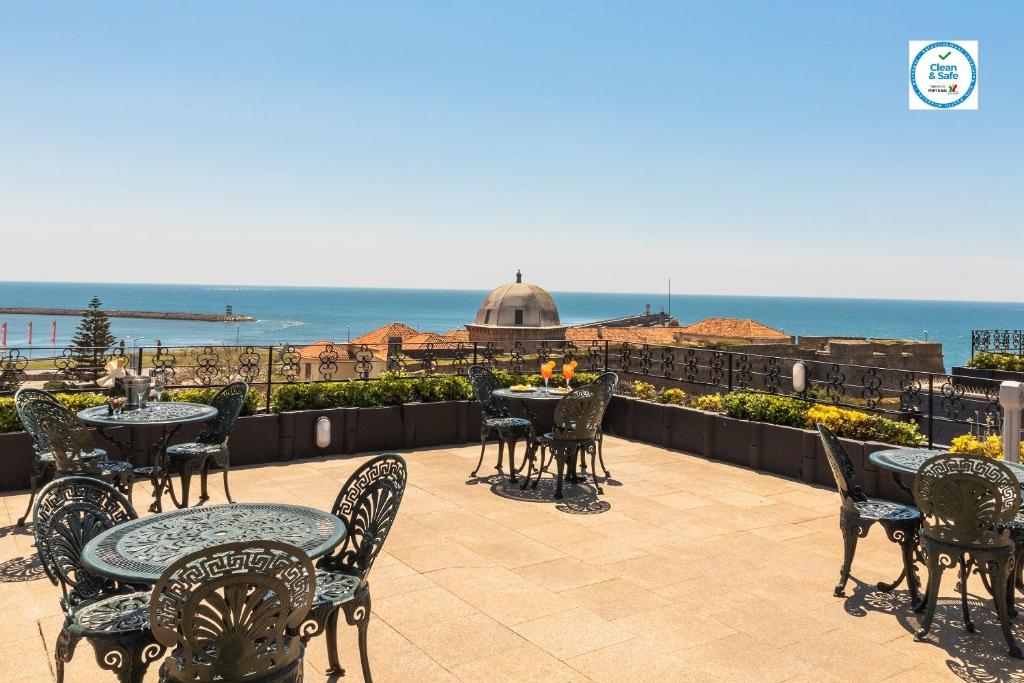 an outdoor patio with tables and chairs and the ocean at Hotel Boa - Vista in Porto