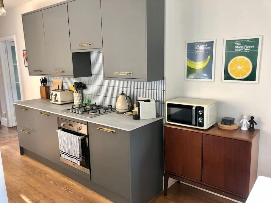 a kitchen with a stove and a microwave at Flat1Hove- renovated, 2BR, patio, beach, free onsite parking in Hove