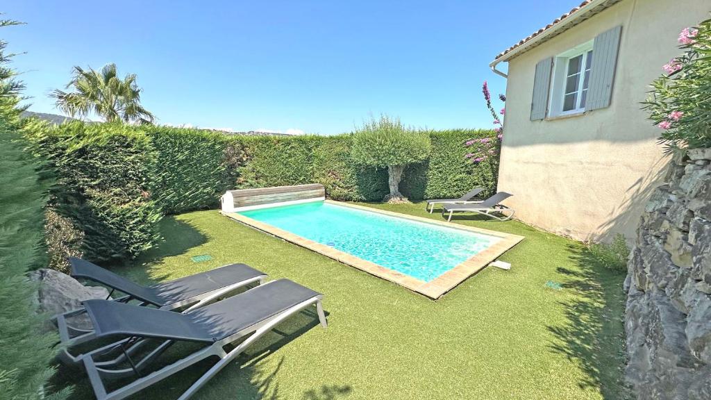 - une piscine avec 2 chaises longues à côté d'une maison dans l'établissement Restanques - Beauchêne, à Sainte-Maxime