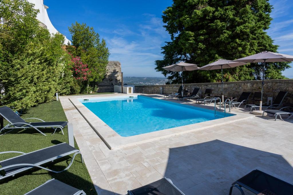 a pool with chairs and umbrellas in a yard at Pousada de Ourém - Fátima in Ourém