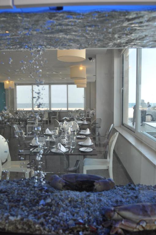 a dining room with tables and chairs and windows at Hotel Mar Bravo in Nazaré