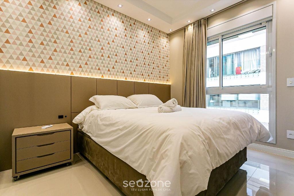 a bedroom with a large bed with a brick wall at Sophisticated fit with 3 suites Jurere LES403 in Florianópolis