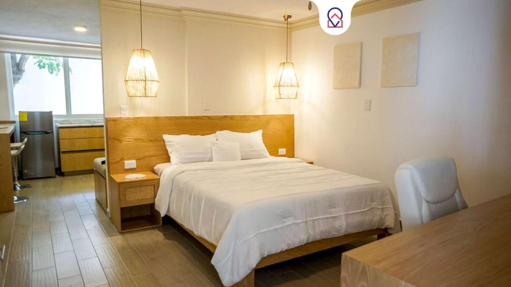 克雷塔罗Modern Apt with Workspace in Central Queretaro的酒店客房配有一张床、一张书桌和一间厨房。