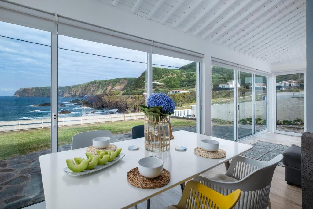a dining room with a table with a view of the ocean at Serenity Villa in Mosteiros